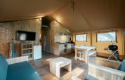Indretning af Nomad XL safari-telt på Camping de Italiaanse Meren i Holland med træmøbler og køkken.
