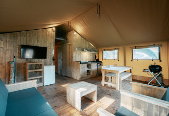Interieur van Nomad XL safaritent bij Camping de Italiaanse Meren in Nederland met houten meubilair.