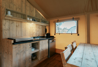 Cocina y comedor dentro de la tienda safari Nomad XL en Camping de Italiaanse Meren, Países Bajos.