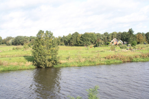 Blick auf den Fluss und das grüne Land beim Baumhaus Ooievaarsnest auf Camping de Koeksebelt, Niederlande.