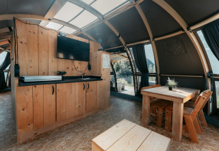 Interior del lodge Panorama en Camping de Italiaanse Meren, Países Bajos, con muebles de madera y luz natural.