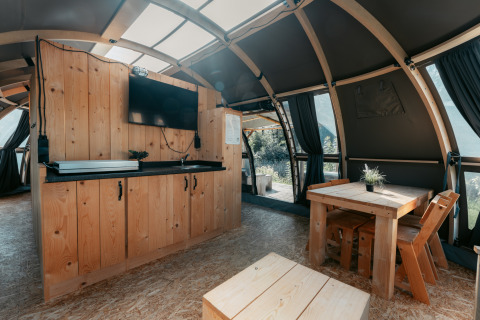 Interior del lodge Panorama en Camping de Italiaanse Meren, Países Bajos, con muebles de madera y luz natural.
