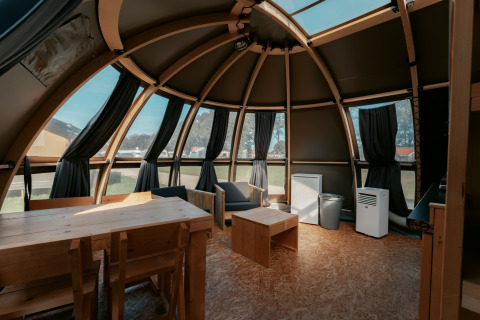 Interior de la cabaña Panorama en Camping de Italiaanse Meren, Países Bajos, con muebles y ventanales de madera.