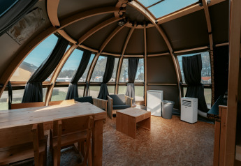 Innenansicht der Panorama-Lodge auf Camping de Italiaanse Meren, Niederlande, mit Holzmöbeln und Fenstern.