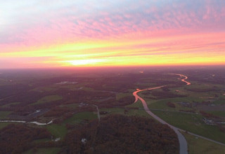Vista al atardecer desde la casa árbol Ooievaarsnest en Camping de Koeksebelt en los Países Bajos, con río.