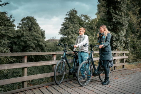 Due persone in sosta con biciclette su un ponte di legno a Camping de Italiaanse Meren, Gelderland, Paesi Bassi.