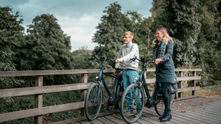 Dos personas descansan con bicicletas en un puente de madera en Camping de Italiaanse Meren, Gelderland, Países Bajos.