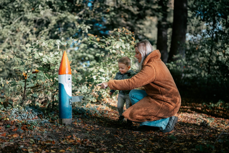 Une femme et un enfant découvrent une sculpture peinte en forêt à Camping de Italiaanse Meren, Pays-Bas.