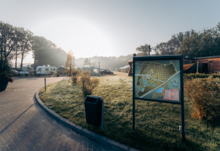 Camping de Italiaanse Meren in Gelderland, Nederland, met kampeerkaart, caravans, houten chalets en ochtendzon.