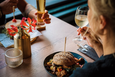 Zwei Personen genießen Burger und Wein auf Camping de Italiaanse Meren, Ferienpark in Gelderland, Niederlande.