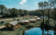 Udsigt over Camping de Italiaanse Meren feriepark i Gelderland, Holland, med telte ved en sø og skov.