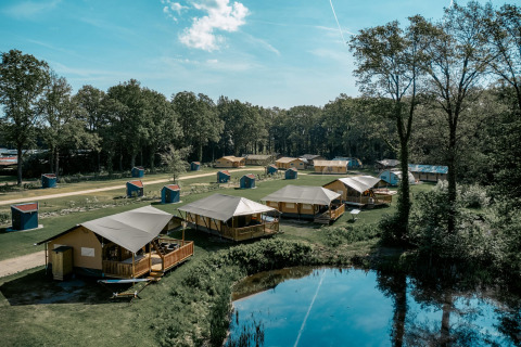 Udsigt over Camping de Italiaanse Meren feriepark i Gelderland, Holland, med telte ved en sø og skov.