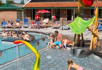 Bambini e adulti si divertono in piscina al Camping de Koeksebelt nei Paesi Bassi in una giornata soleggiata.