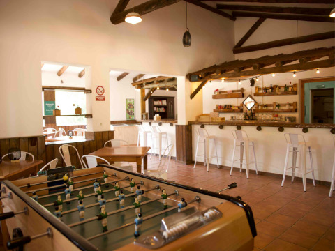 Sala interior en Huttopia Parque de Doñana, Andalucía, con futbolín, barra de bar y zona de comedor.