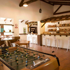 Sala interior en Huttopia Parque de Doñana, Andalucía, con futbolín, barra de bar y zona de comedor.