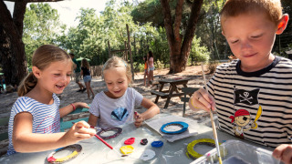 Des enfants peignent en plein air sous les arbres au Huttopia Parque de Doñana en Andalousie, Espagne.