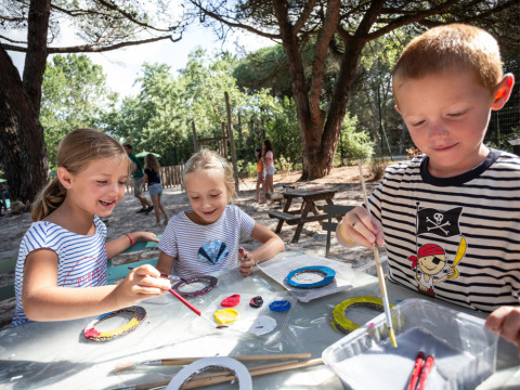 Niños pintando al aire libre bajo los árboles en Huttopia Parque de Doñana, Andalucía, España.