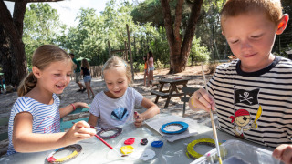 Niños pintando al aire libre bajo los árboles en Huttopia Parque de Doñana, Andalucía, España.