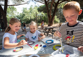 Niños pintando al aire libre bajo los árboles en Huttopia Parque de Doñana, Andalucía, España.