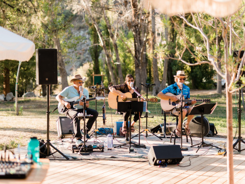 Band dal vivo che suona all'aperto tra gli alberi a Huttopia Parque de Doñana, Andalusia, Spagna.