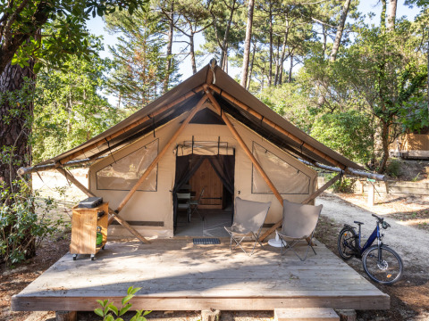 Tenda di lusso a Huttopia Parque de Doñana, Andalusia, Spagna, con veranda, sedie e bicicletta.