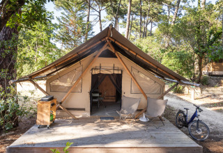 Tienda de lujo en Huttopia Parque de Doñana, Andalucía, España, con terraza, sillas y bicicleta.