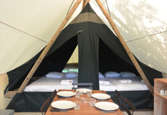 Innenansicht eines Canadienne Safari-Zeltes mit Betten und Esstisch im Huttopia Parque de Doñana, Spanien.