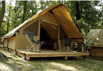 Canadienne safari tent featuring a wooden deck and two camping chairs in a lush, wooded campground.