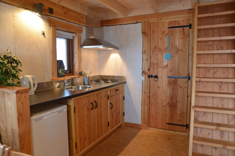 Treehouse at Camping de Koeksebelt in the Netherlands, with a compact kitchen, wooden stairs, and door.