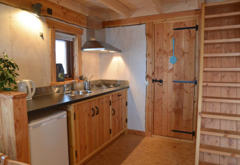 Casa del árbol en Camping de Koeksebelt, Países Bajos, con cocina, escalera y puerta de madera.