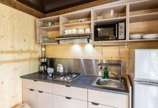 Moderne kitchenette in Chalet Portland bij Huttopia Parque de Doñana, Spanje, met fornuis, magnetron en koelkast.