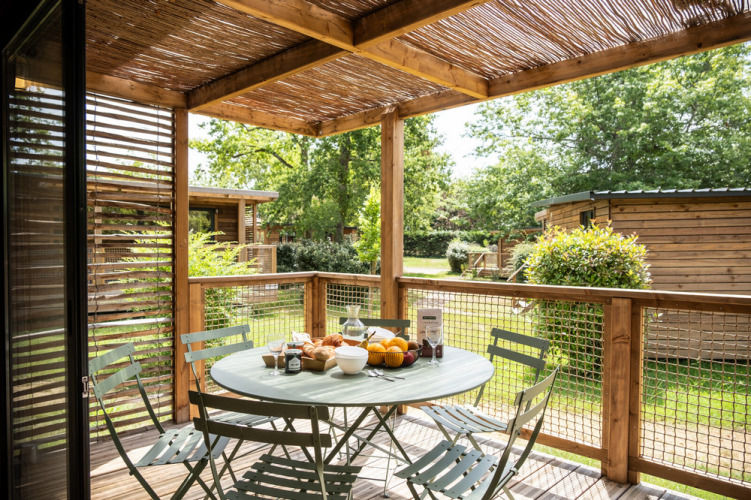 Gemütliche Holzterrasse mit Esstisch am Chalet Portland im Huttopia Parque de Doñana, Spanien.