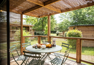 Udendørs træterrasse med bord og stole på Chalet Portland i Huttopia Parque de Doñana, Spanien.
