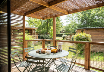 Gemütliche Holzterrasse mit Esstisch am Chalet Portland im Huttopia Parque de Doñana, Spanien.