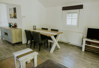 Salon moderne à la Forest Lodge du Camping Si-Es-An, Pays-Bas, avec table à manger et coin TV.