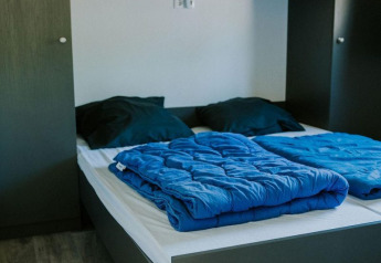 Camera moderna alla Forest lodge al Camping Si-Es-An nei Paesi Bassi, con letto matrimoniale e armadi.