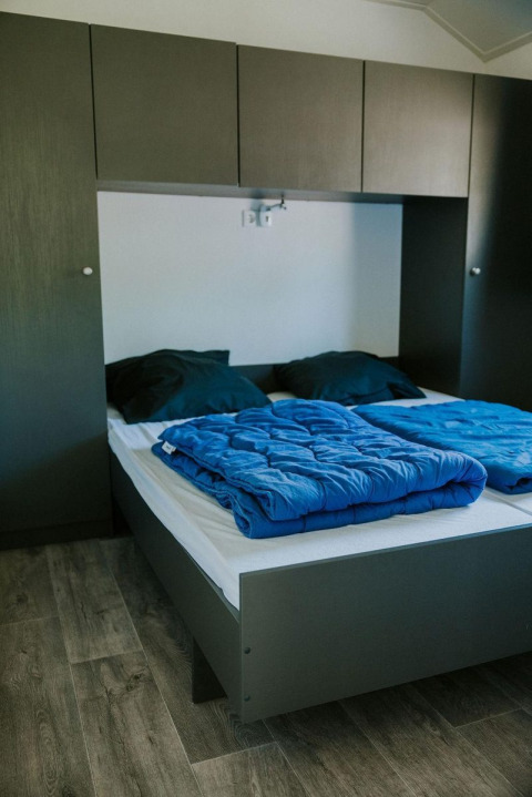 Modern slaapkamerinterieur in Forest lodge bij Camping Si-Es-An in Nederland met tweepersoonsbed.