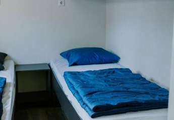 Camera moderna con due letti singoli, pavimenti in legno e biancheria blu alla Forest Lodge, Camping Si-Es-An.