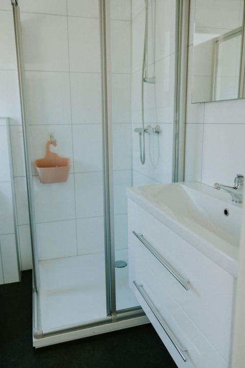 Salle de bain moderne avec douche vitrée, meuble lavabo blanc et miroir à Forest lodge, Camping Si-Es-An.