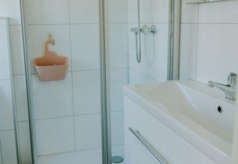 Moderne badkamer met glazen douche, wit wastafelmeubel en spiegel in de Forest lodge, Camping Si-Es-An.