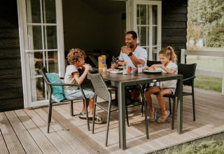 Une famille partage un repas sur la terrasse du Forest Lodge au Camping Si-Es-An, aux Pays-Bas.