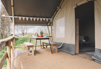 Safari tent deck with wooden benches and table, outdoor dining under canopy, surrounded by nature.