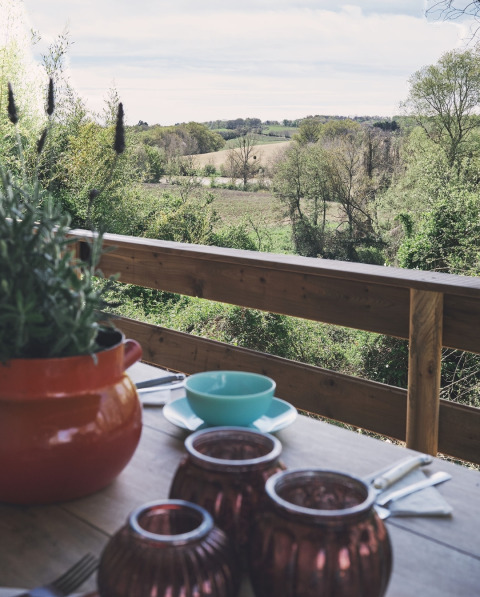Zicht vanuit een safaritent bij Camping d'Artagnan in Frankrijk met gedekte tafel en groen landschap.