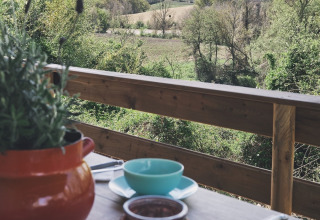 Vista da una tenda safari al Camping d'Artagnan in Francia con tavolo apparecchiato e campagna verde.