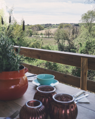 Vista desde una tienda safari en Camping d'Artagnan en Francia con mesa puesta y paisaje verde.