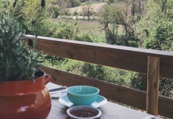 Vista da una tenda safari al Camping d'Artagnan in Francia con tavolo apparecchiato e campagna verde.
