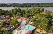 Aerial view of Huttopia Lac de l'Uby - Gers holiday park with a pool, lake and greenery in Occitanie, France.