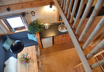 Vista dall’alto dell’interno accogliente di una casa sull’albero con cucina e tavolo a Camping de Koeksebelt.