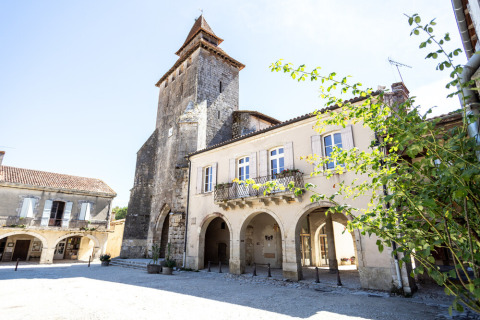 Piazza storica vicino a Cazaubon, Occitania, Francia, con edifici in pietra e torre campanaria antica.