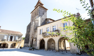 Historischer Platz nahe Cazaubon, Occitanie, Frankreich, mit alten Steingebäuden und einem Kirchturm.
